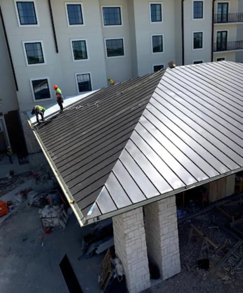Crew installing standing seam metal roof panels on a commercial project in Calverton